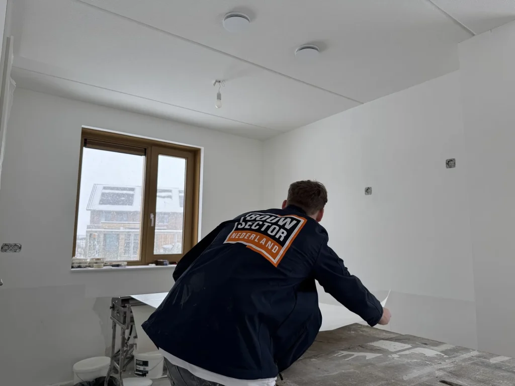 Behanger van Bouwsector Nederland pakt een baan vlies van de plaktafel in een nieuwe woning